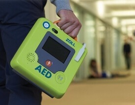 Man carrying Zoll AED down hallway