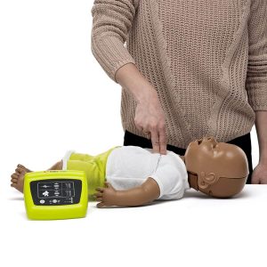 Man demonstrating chest compressions on dark skinned, infant CPR manikin with wireless CPR feedback monitor in the foreground